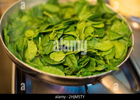Spinaci in una pentola con fuoco acceso Foto Stock