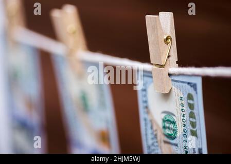 Le fatture americane del cento-dollaro sono appese su una corda con i clothespins di legno. Concetto di riciclaggio di denaro. Soldi sporchi. Foto Stock