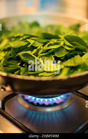 Spinaci in una pentola con fuoco acceso Foto Stock