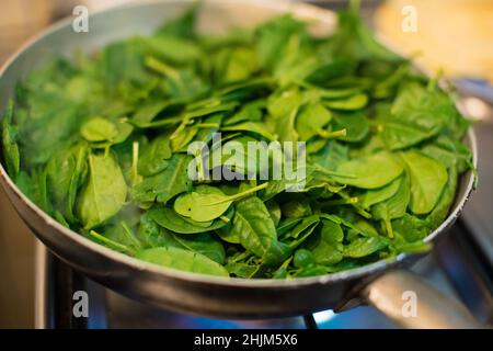 Spinaci in una pentola con fuoco acceso Foto Stock