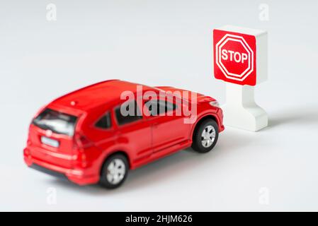 Un cartello auto e stop Road su sfondo bianco. Auto giocattolo parcheggiata accanto a un cartello di stop giocattolo. Leggi sul traffico. Foto Stock