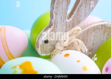 Uova di Pasqua colorate e coniglio di legno. Coniglio carino tra le uova di Pasqua. Foto Stock