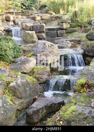 Piccolo torrente scorre attraverso un ambiente roccioso, sfondo sfocato. Le pietre sono in parte esagerate di muschio Foto Stock