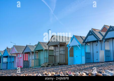 Una fila di tradizionali capanne inglesi sulla spiaggia, dipinte in vibranti colori pastello a Herne Bay visto in una soleggiata Domenica mattina di gennaio. Foto Stock