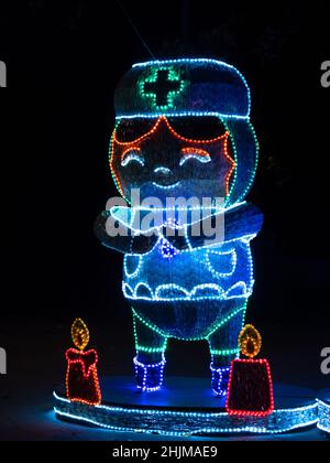 Medellin, Antioquia, Colombia - Gennaio 4 2022: Decorazione con luci colorate di un ragazzo in un vestito di una infermiere con candele Foto Stock