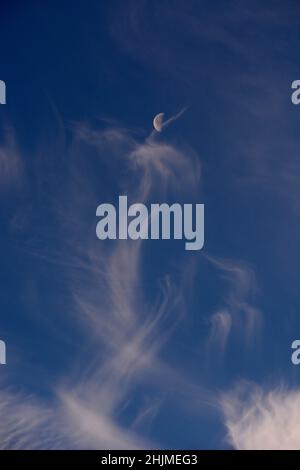 Una luna dell'ultimo quarto, a volte chiamata mezzaluna, condivide il cielo con le nubi di cirro spia sopra Santa Fe, New Mexico. Foto Stock