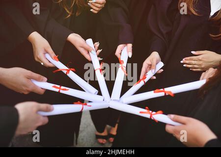 laureati in abiti neri con diplomi o certificati di laurea presso un istituto di istruzione superiore. Foto Stock