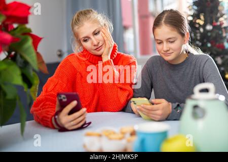 Figlia e mamma scrivono messaggi di saluto al telefono durante le vacanze di Natale Foto Stock