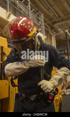 MAR DELLE FILIPPINE (Gen. 29, 2022) Boatswain’s Mate 1st Classe Tony Martinez, di Miami, assegnato alla nave d’assalto anfibio dispiegata in avanti USS America (LHA 6), sorrega un autorespiratore nella baia di hangar della nave durante una trivella antincendio della zona macchine. L'America, nave principale dell'America Amphibious Ready Group, insieme all'unità Marine Expeditionary 31st, sta operando nell'area di responsabilità della flotta USA 7th per migliorare l'interoperabilità con alleati e partner e servire come forza di risposta pronta per difendere la pace e la stabilità nella regione IndoPacifico. (STATI UNITI Navy phot Foto Stock