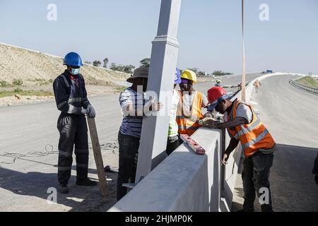 Nairobi, Kenya. 26th Jan 2022. I lavoratori edili fissano i poli luminosi su una sezione di un cantiere del progetto Nairobi Expressway lungo la strada Mombasa. La costruzione dell'autostrada a pedaggio lunga 27,1km, la Nairobi Expressway continua e si prevede che sarà completata nel giugno 2022. La superstrada di Nairobi è destinata a decongest la città di Nairobi fornendo trasporti più veloci e affidabili. Credit: SOPA Images Limited/Alamy Live News Foto Stock