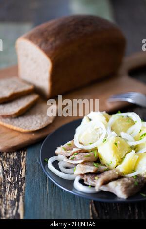 Pane di segale fatto in casa a fette con un piatto di patate e aringhe. Vista frontale. Foto Stock