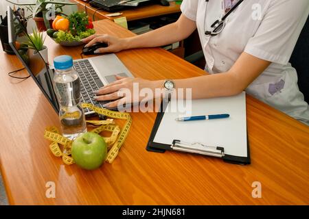 Donna dietista con metro a nastro che lavora su un piano di dieta. Perdita di peso Foto Stock