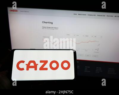 Persona che tiene smartphone con il logo della società di vendita al dettaglio britannica Cazoo Ltd. Sullo schermo di fronte al sito web. Mettere a fuoco sul display del telefono.