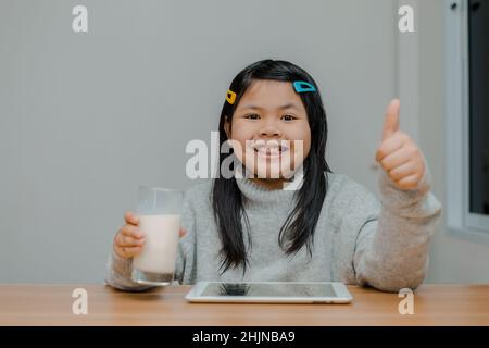 Ragazza asiatica che ha il latte prima di dormire sorridendo felicemente Foto Stock