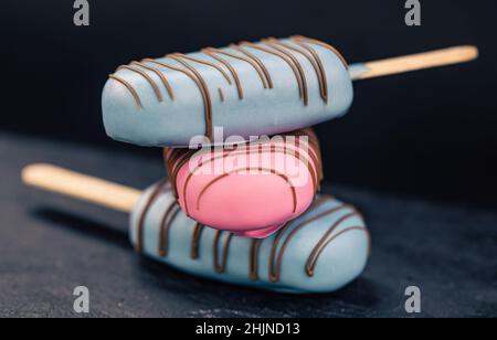 Dessert in forma di gelato alla pop-sicle ricoperto di cioccolato rosa e blu. Foto Stock