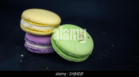 Macaron o macaron francesi dolci e colorati su sfondo nero. Foto Stock