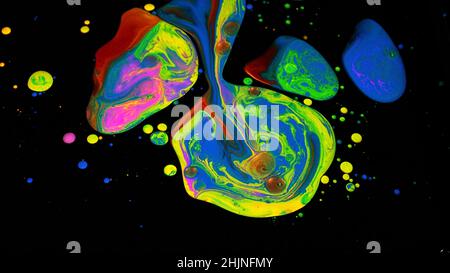 Superficie fantastica con vernici acriliche multicolore mescolate su sfondo nero. Primo piano di gocce di inchiostro acrilico brillante che assomiglia a sorprendente contrasto stai Foto Stock