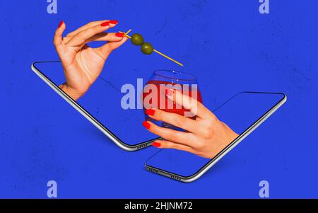 Le mani femminili con il vetro del cocktail sporgono gli schermi del telefono isolati su sfondo blu brillante del neon. Concetto di gusto, bevande alcoliche Foto Stock