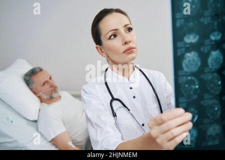 Medico concentrato che esamina le scansioni RM dell'uomo malato Foto Stock