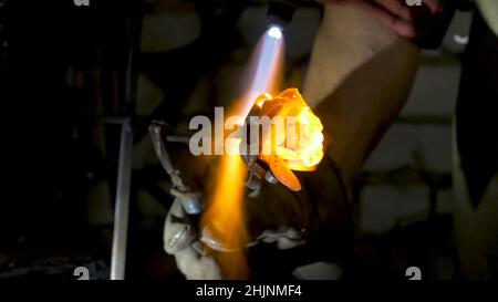 Il fabbro allinea le foglie di ferro rosa e fa la forma finale del fiore. Il fabbro fa rosa di ferro. Foto Stock