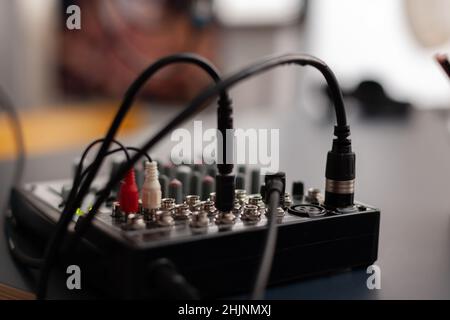 Primo piano dello strumento di registrazione professionale sulla scrivania. Mixer audio per trasmissioni live. Console elettronica podcast in casa studio. Stazione da tavolo di missaggio per la trasmissione utilizzata per registrare suoni e doppiaggio. Foto Stock