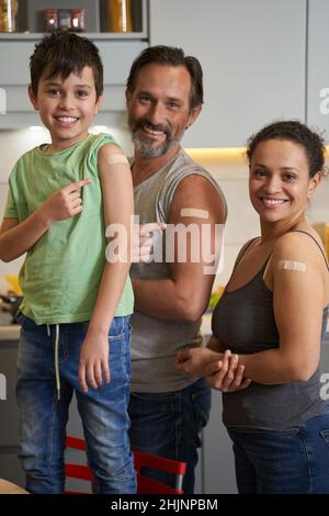 Padre, madre e figlio con cerotti sulle spalle Foto Stock