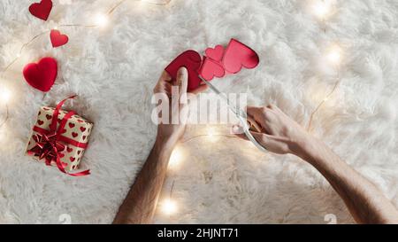 Guy prepara il cuore rosso con carta su tappeto bianco neve Foto Stock