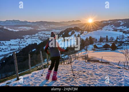 Donna anziana, escursioni sno al tramonto nella zona di Bregenzer Wald di Vorarlberg, Austria con vista spettacolare sul Monte Saentis su sa mare di nebbia, Svizzera Foto Stock