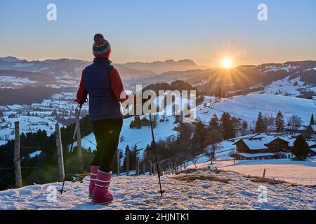 Donna anziana, escursioni sno al tramonto nella zona di Bregenzer Wald di Vorarlberg, Austria con vista spettacolare sul Monte Saentis su sa mare di nebbia, Svizzera Foto Stock