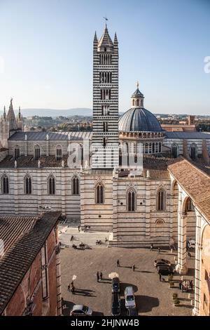 Vista sul Duomo di Siena, Toscana, Italia. Piazza del duomo con auto e gente; Campanile e cupola. Foto Stock