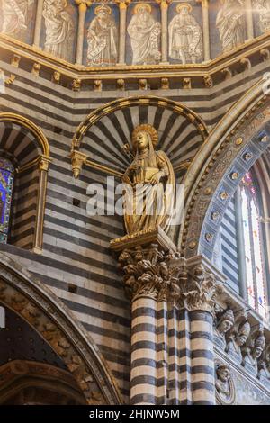 Statua in stucco dorata di Santa Caterina da Siena nel Duomo di Siena. Sopra di lei ci sono alcuni dipinti di profeti e patriarchi e dietro di lei ci sono Foto Stock