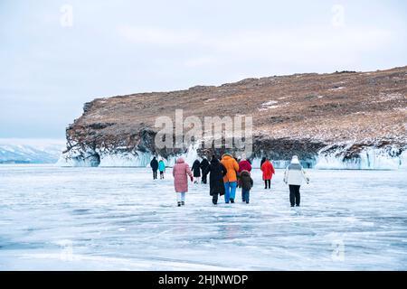 Gruppo di turisti cammina sul ghiaccio per esplorare le grotte di ghiaccio sull'isola di Olkhon. Lago Baikal Foto Stock