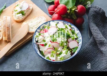 Formaggio casolare con erba cipollina e ravanello appena tagliati. Colazione leggera e nutriente Foto Stock