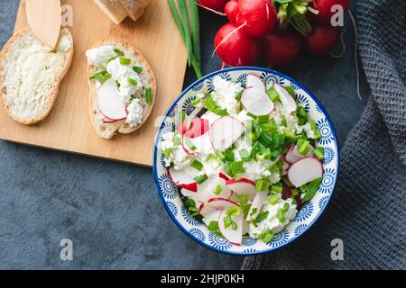 Formaggio casolare con erba cipollina e ravanello appena tagliati. Colazione leggera e nutriente Foto Stock