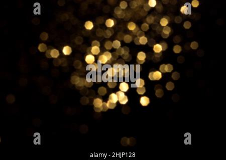 Il bokeh dorato sfocato si illumina su sfondo nero. Stelle scintillanti per festeggiare. Overlay per il tuo progetto Foto Stock