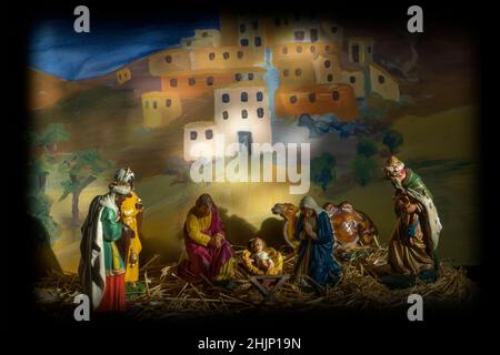 Una scena di presepio creata con figure modello su paglia contro uno sfondo a catena di antiche case, presso la Chiesa di tutti i Santi, Easton, Suffolk Foto Stock