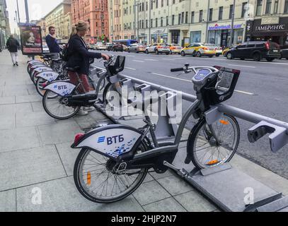 Mosca, Russia, agosto 2019: Un giovane uomo e una donna scelgono le biciclette in un punto di noleggio pubblico nel centro della città su un viale trafficato. Foto Stock