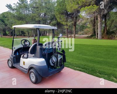 Antalya, Turchia, novembre 2019: Una Golf Car con una borsa di club di golf in pista tra i campi da golf. Qualcuno è seduto sul sedile passeggero. Foto Stock