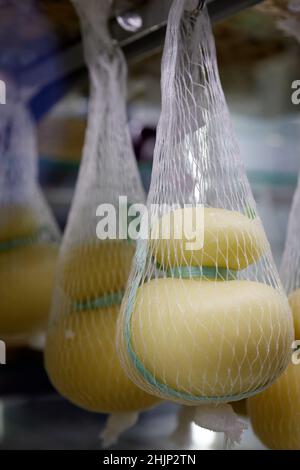 Delizioso Caciocavallo fresco e Scamorza formaggio appeso. Formaggi italiani da vicino. I formaggi sono fatti a mano. La produzione di formaggio Foto Stock