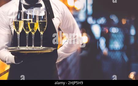 Cameriere che tiene fuori bicchieri di vino frizzante all'evento. Foto Stock