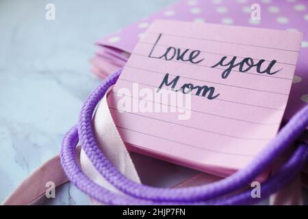 concetto del giorno della madre con il blocco note appiccicoso con il testo e la scatola del regalo sul tavolo Foto Stock