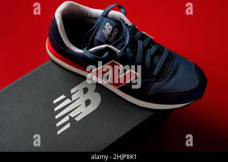 Nuove sneaker Balance 500 blu scuro con la scatola New Balance grigia su sfondo rosso. Scarpe sportive casual da primo piano Foto Stock