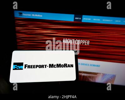 Persona che tiene uno smartphone con il logo della società mineraria statunitense Freeport-McMoRan Inc. Sullo schermo di fronte al sito Web. Mettere a fuoco sul display del telefono. Foto Stock