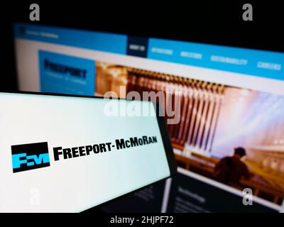 Cellulare con logo della società mineraria statunitense Freeport-McMoRan Inc. Sullo schermo di fronte al sito web aziendale. Messa a fuoco al centro-sinistra del display del telefono. Foto Stock