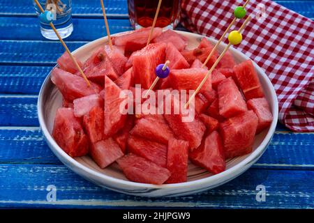 Piccoli pezzi frastagliati di anguria fredda, fresca e dolce su un piatto da portata con bacchette. Cibo sano, fresco e naturale. Frutta di stagione. Foto Stock