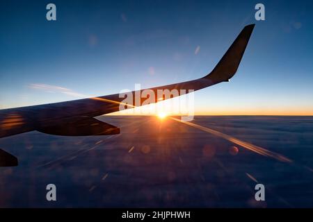 Incredibile tramonto dalla finestra dell'aeroplano con la silhouette ad ala contro il cielo Foto Stock