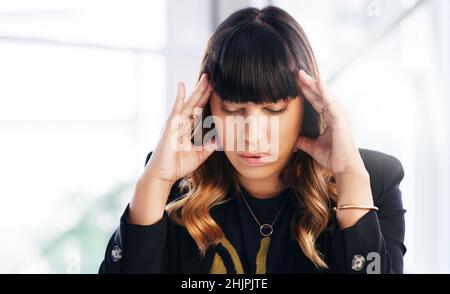 La battaglia del burnout. Shot di una giovane donna d'affari che vive lo stress mentre lavora in un ufficio moderno. Foto Stock