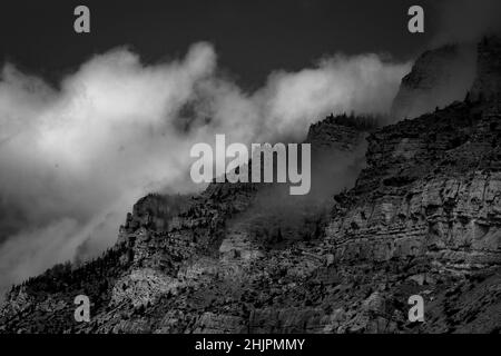 Una foto in scala di grigi di montagne e canyon in una giornata nuvolosa Foto Stock