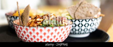 Banner o testata orizzontale con ciotola di poke o pesce crudo marinato condito su un tavolo in un moderno ristorante fusion - piatto tipico hawaiano e inte Foto Stock