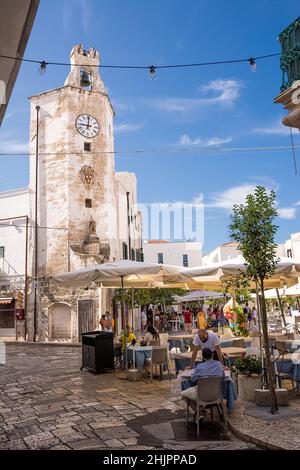 Monopoli, Italia - 20 agosto 2021: Caratteristico orologio a torre e piazza con gazebo bar e turisti nel centro di Monopoli (Puglia) Foto Stock